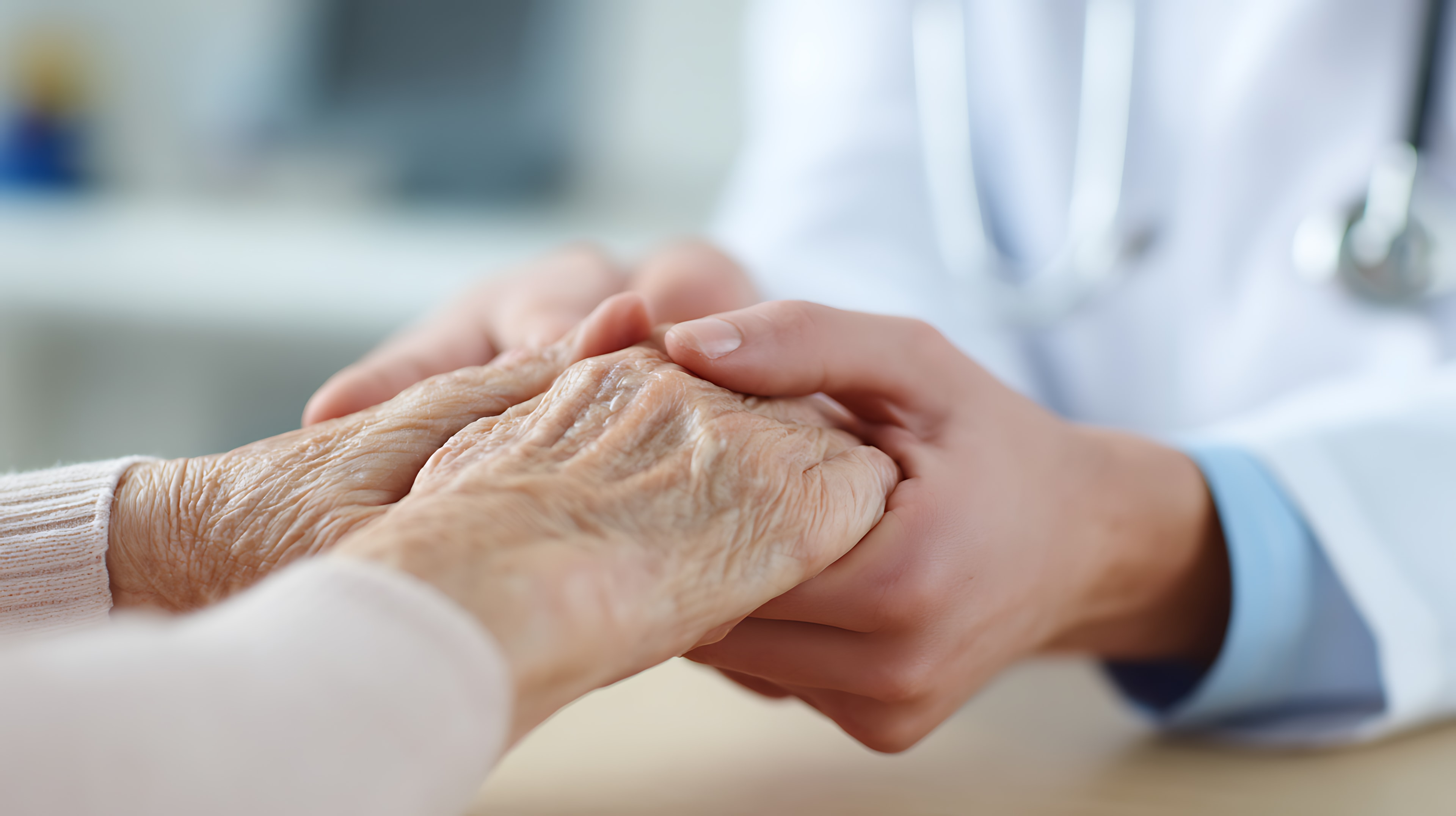 Caregiver holding elderly patient's hand in compassionate hospice care