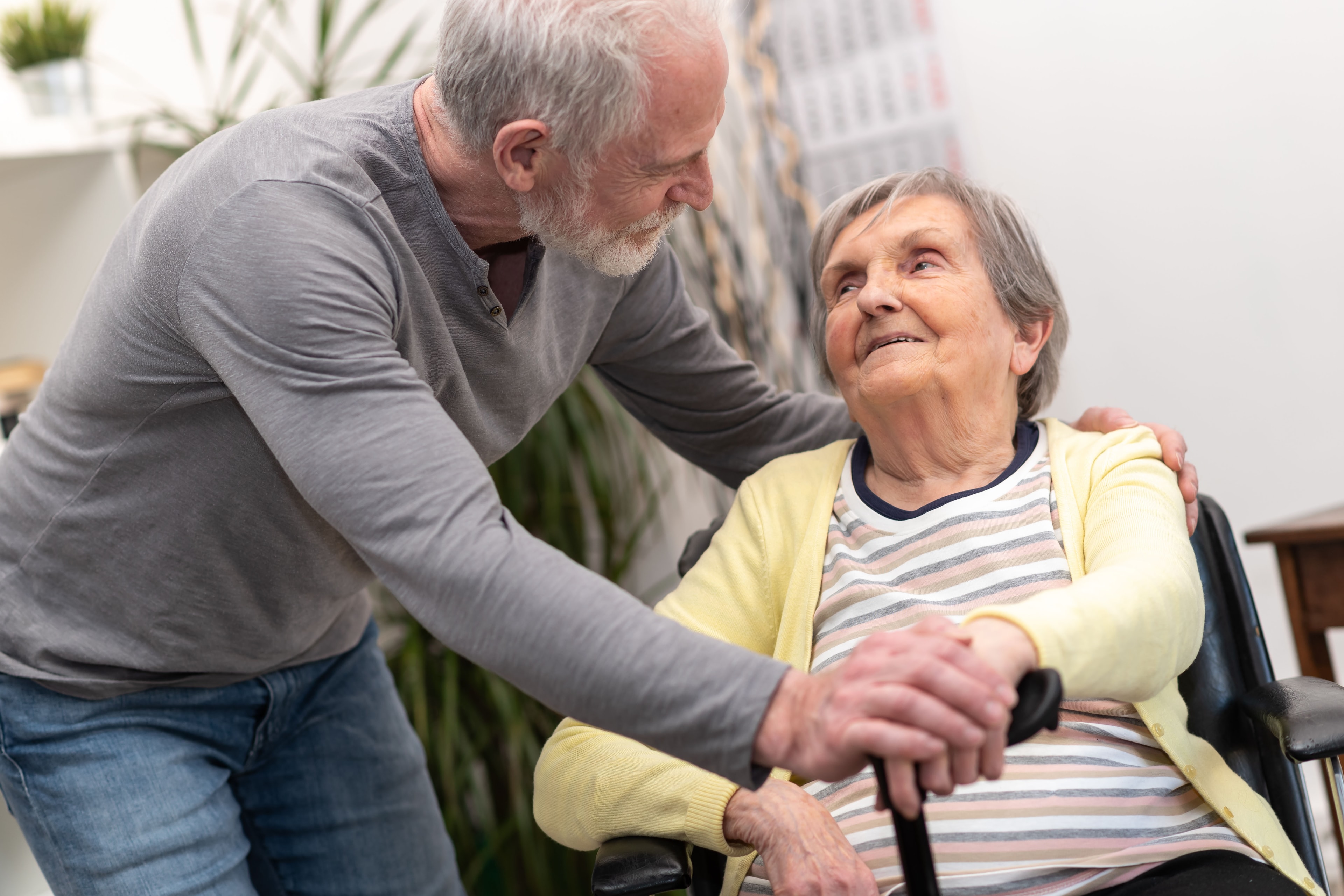 Family member leaning in warmly to speak with an elderly woman in a wheelchair.