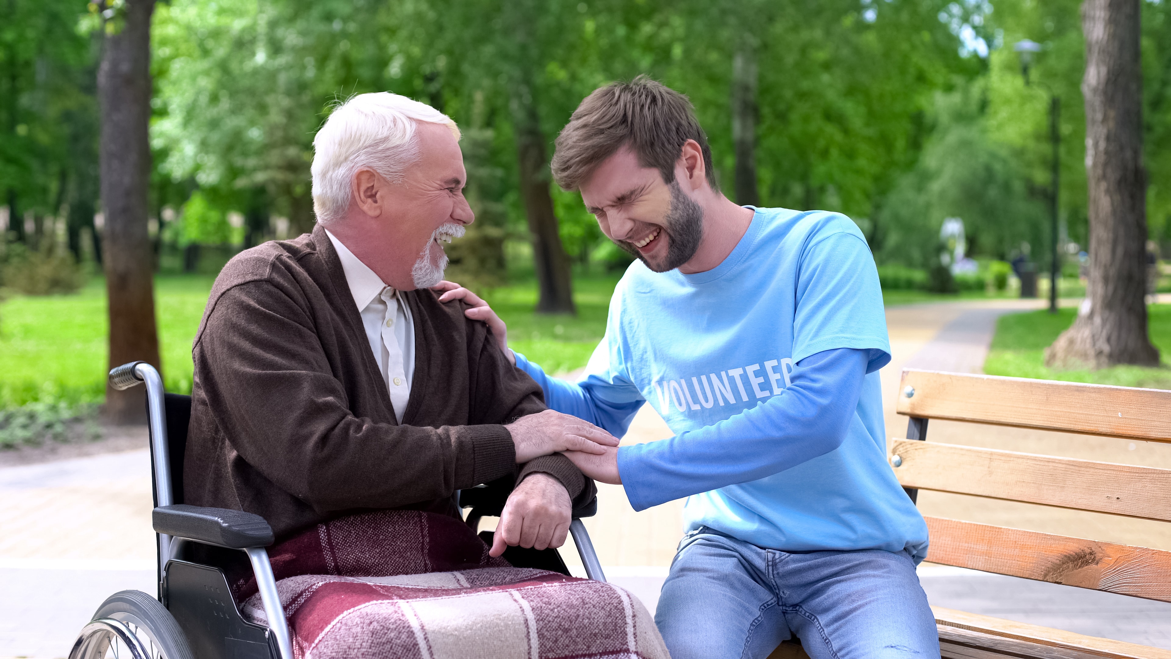 Volunteer and elderly man sharing a laugh together in a park